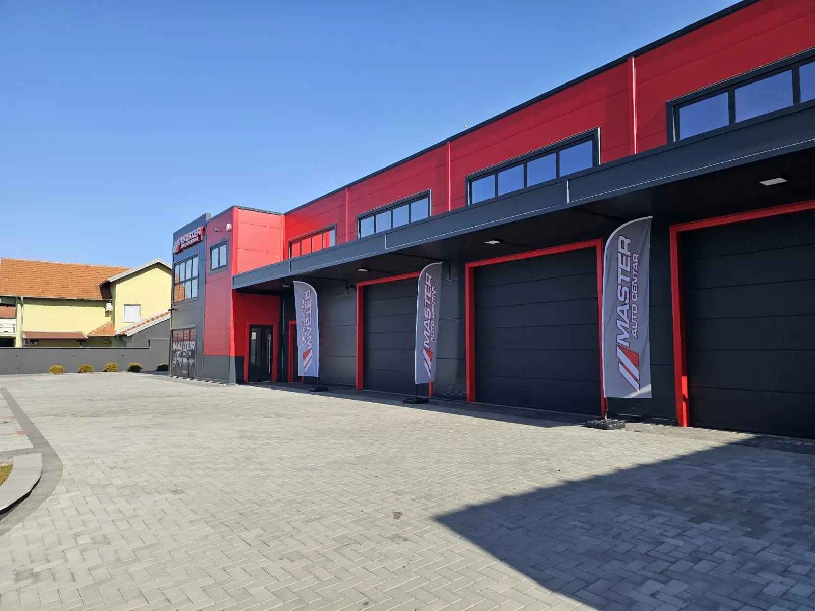Hala Master Auto Centra sa crvenom fasadom i sekcionim vratima